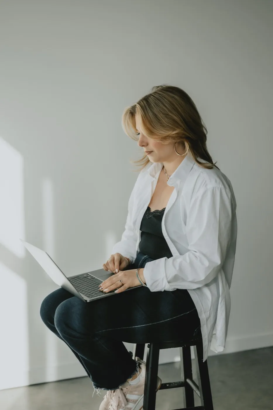 Clémence Tillerot sitting on a stool, working on her laptop