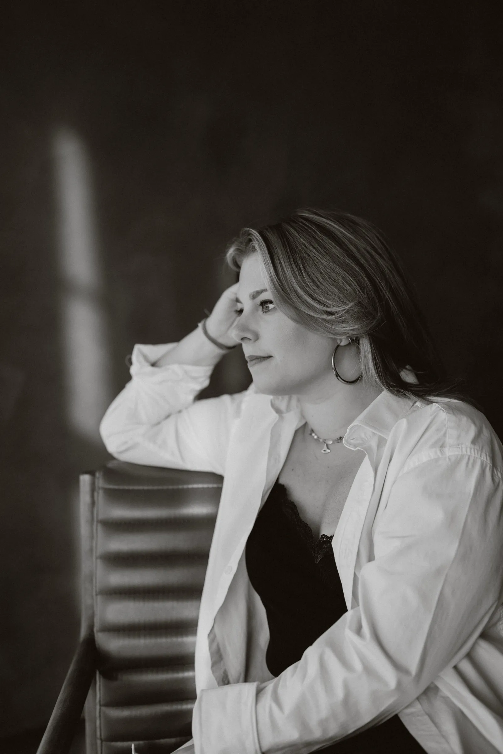 Clémence Tillerot in a dark room, hand in her hair, deep in thought