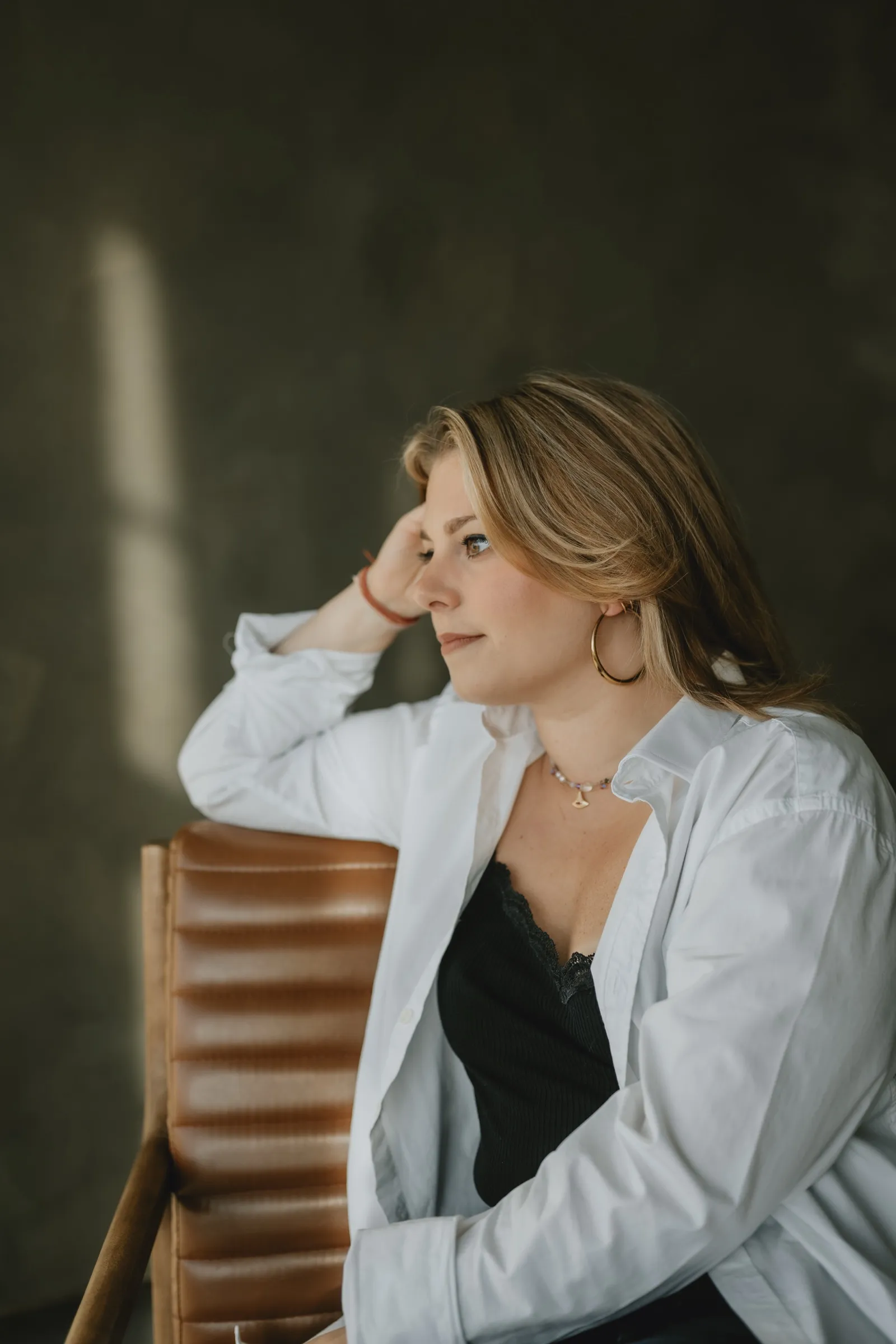 Clémence Tillerot sitting in an armchair, chin in her hand, looking ahead