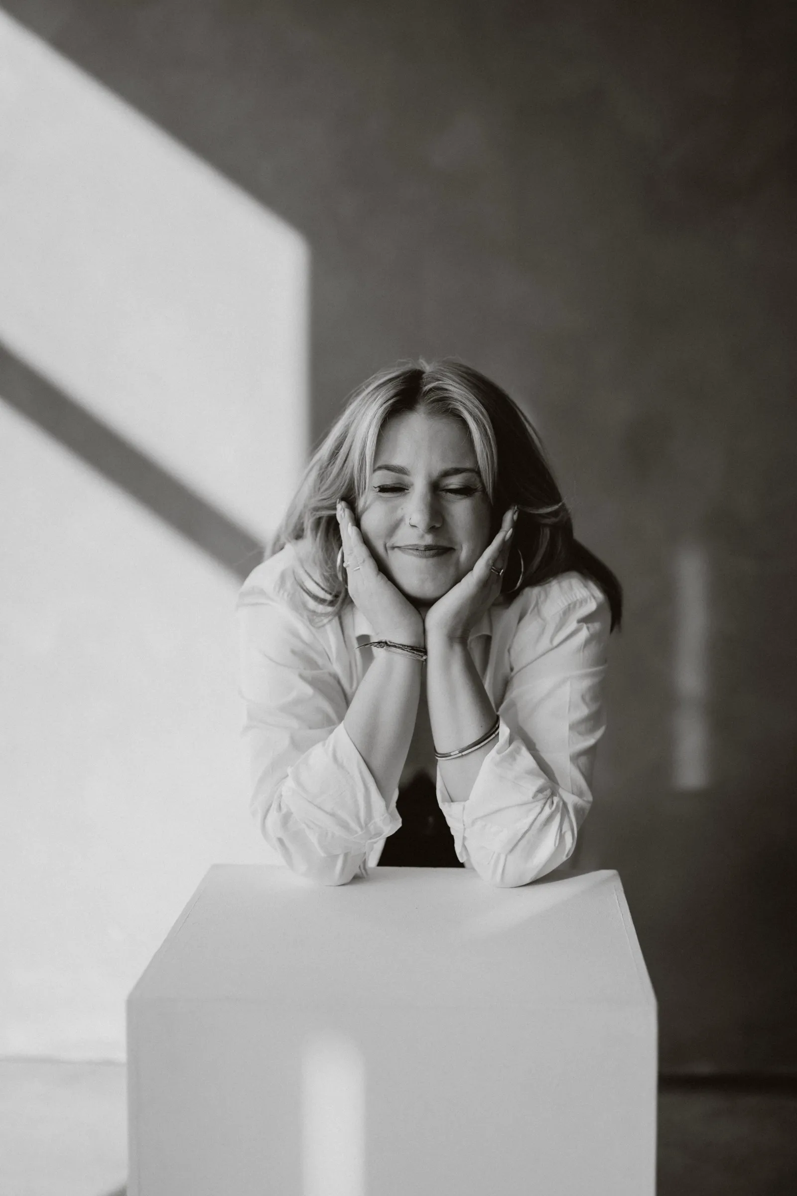 Clémence Tillerot leaning on a white plinth, eyes closed, smiling