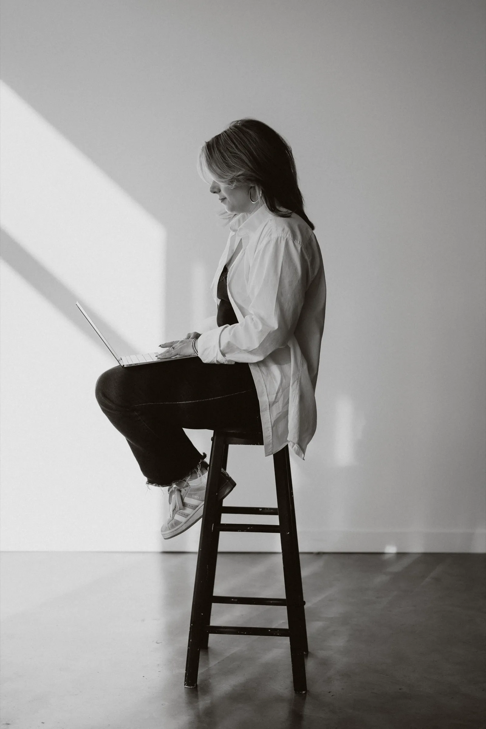 Clémence Tillerot sitting on a stool, working on her laptop