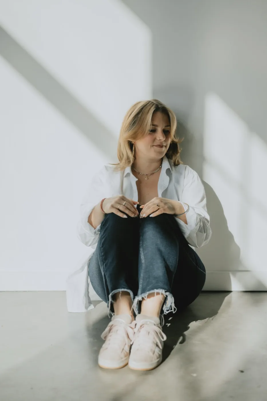 Clémence Tillerot sitting on the floor against a white wall, smiling