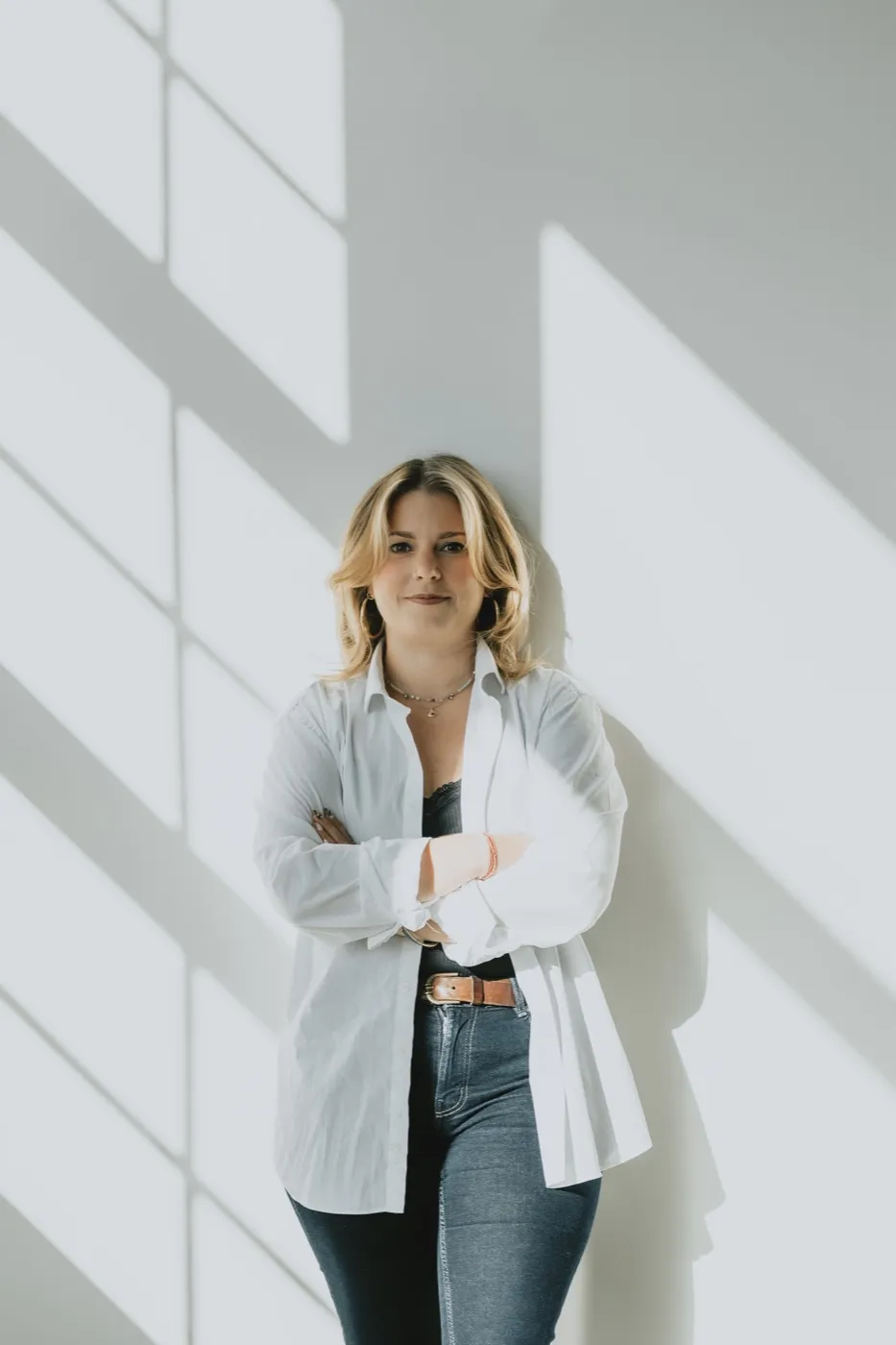 Clémence Tillerot standing against a sunlit wall, arms crossed